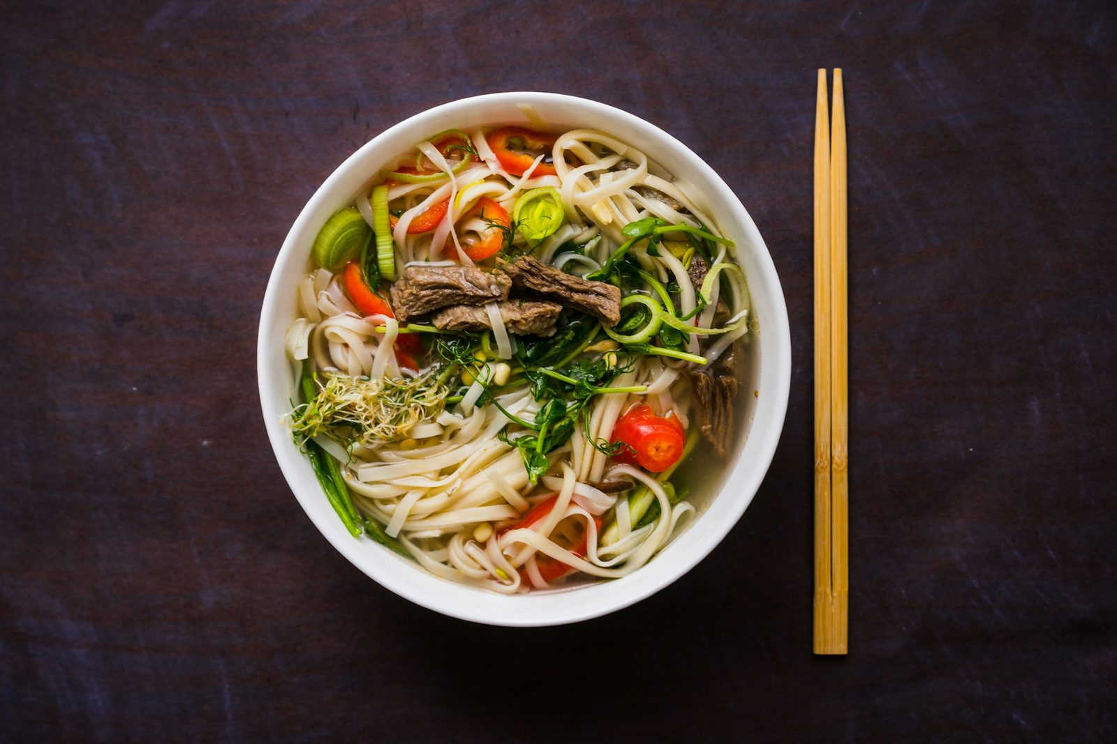 Mexican Birria Ramen, a bowl of noodle soup with chopsticks on the side