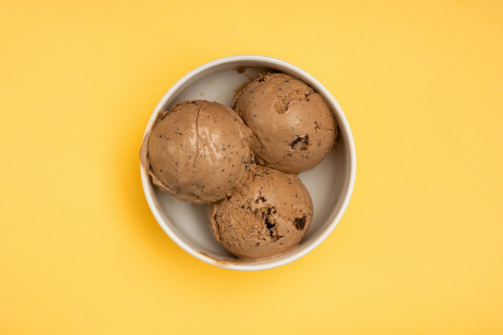 Coffee Ice Cream, three scoops of ice cream in a bowl on a yellow background